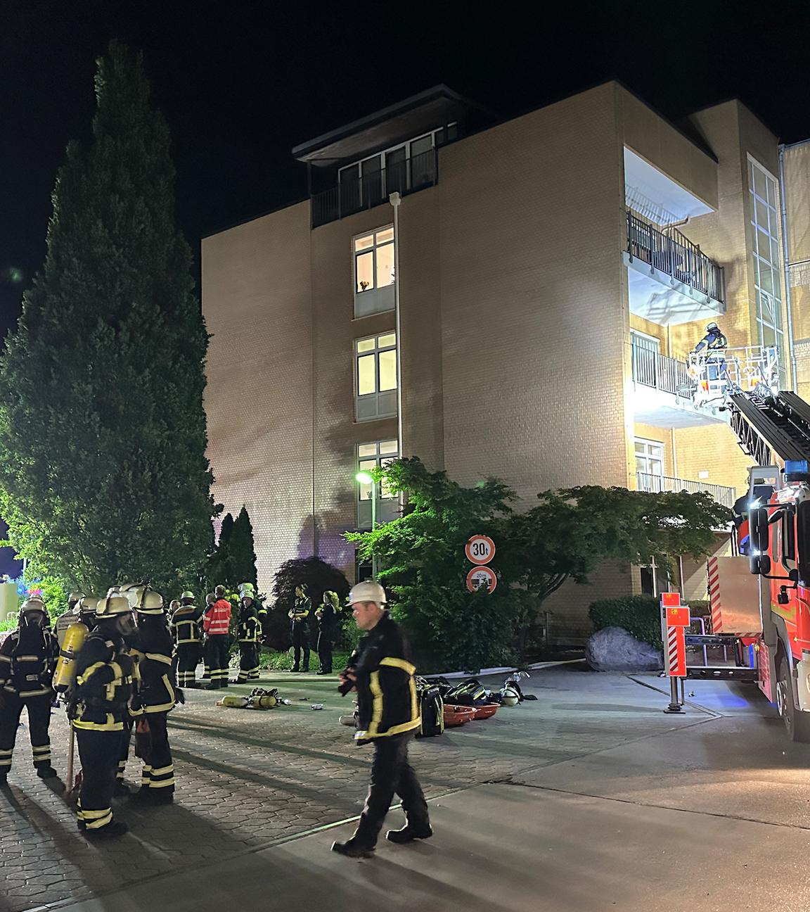 Feuerwehrleute mit Atemschutzgerät und einem Leiterwagen arbeiten am Marienkrankenhaus im Hamburger Stadtteil Hohenfelde. 