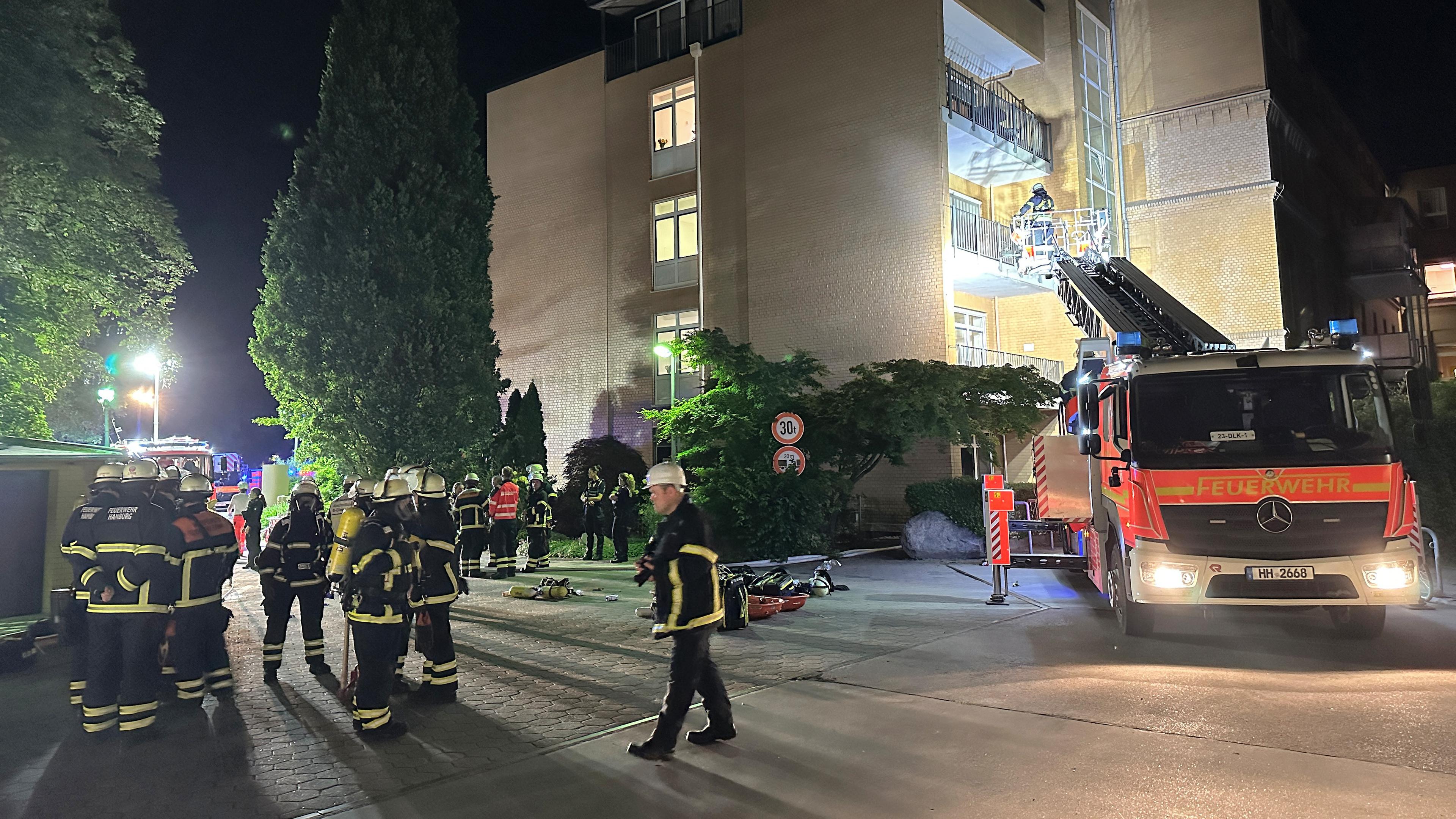 Feuerwehrleute mit Atemschutzgerät und einem Leiterwagen arbeiten am Marienkrankenhaus im Hamburger Stadtteil Hohenfelde. 