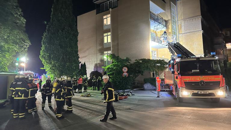 Feuerwehrleute mit Atemschutzgerät und einem Leiterwagen arbeiten am Marienkrankenhaus im Hamburger Stadtteil Hohenfelde. 