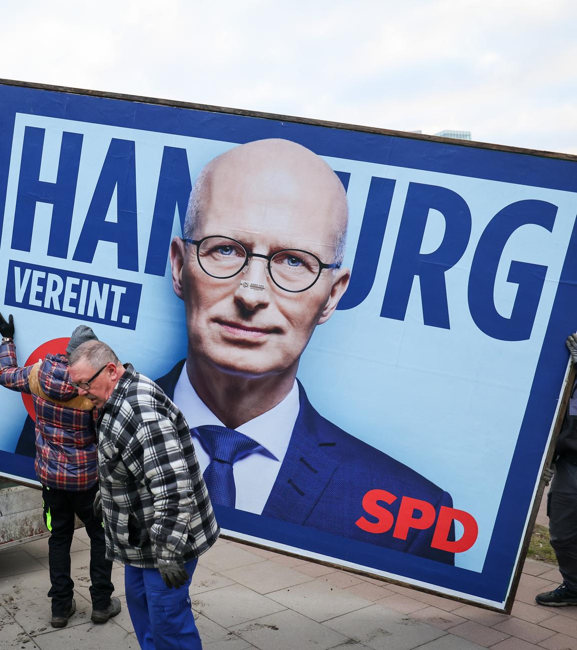 Mitarbeiter eines Unternehmens für Plakatwerbung bauen eine Wahlplakat der SPD zur Bürgerschaftswahl ab.