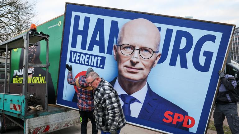 Mitarbeiter eines Unternehmens für Plakatwerbung bauen eine Wahlplakat der SPD zur Bürgerschaftswahl ab.