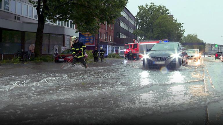 Ein Auto fährt auf einer überschwemmten Straße in Hamburg.