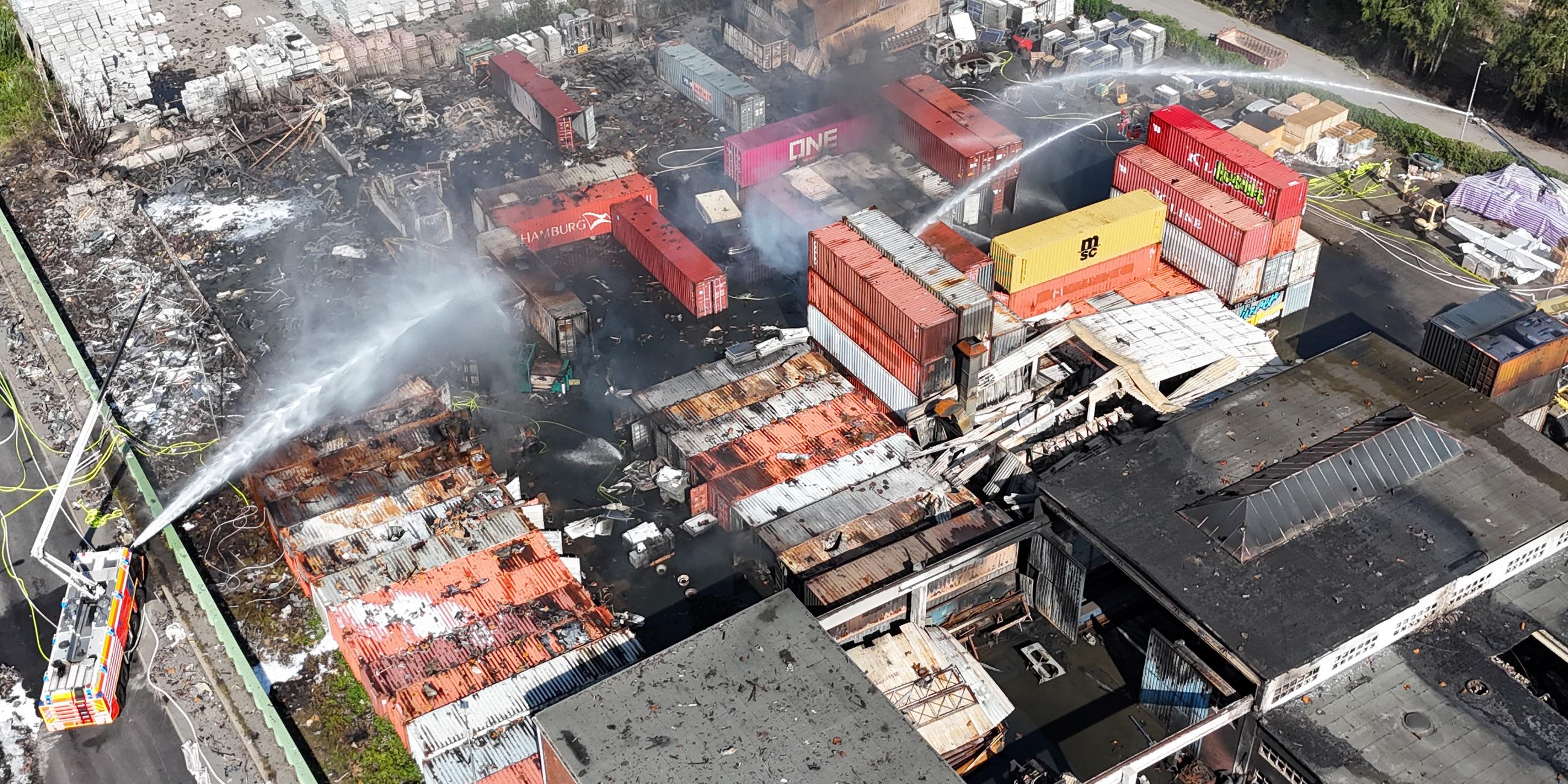 26.08.2025, Hamburg: Einsatzkräfte der Feuerwehr löschen einen Brand in einem Industriegebiet im Hamburger Hafen, in dem am Vortag ein Großbrand ausgebrochen war. 