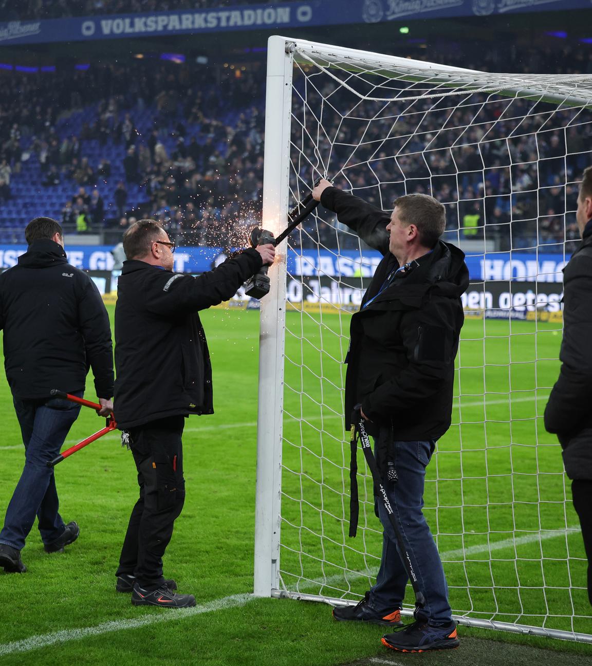 Stadionmitarbeiter entfernen ein Fahrradschloss vom Torpfosten