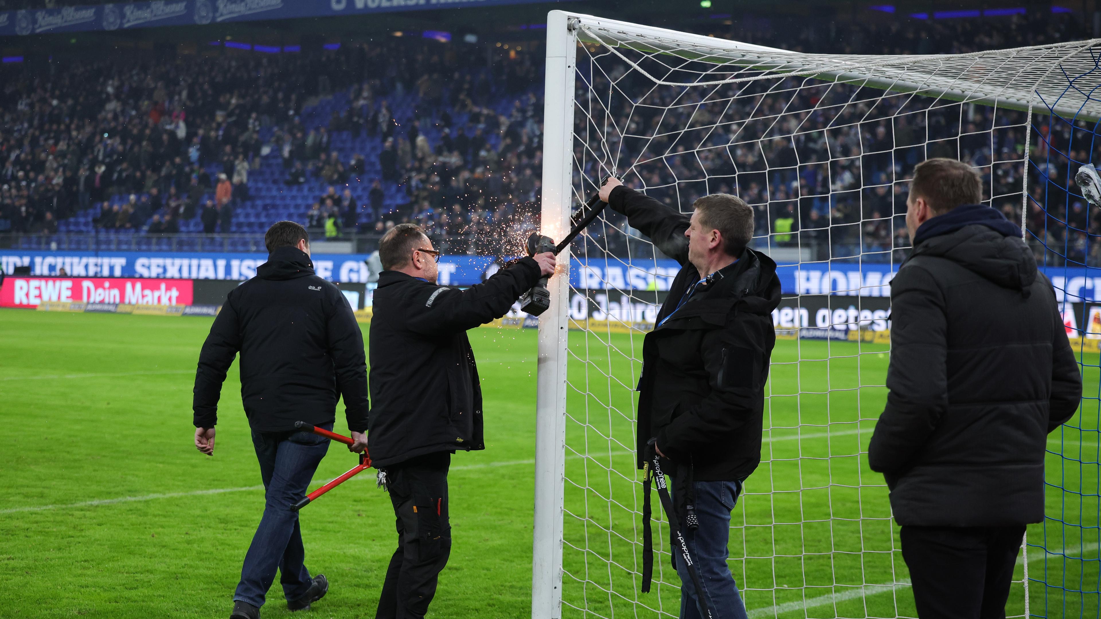 Stadionmitarbeiter entfernen ein Fahrradschloss vom Torpfosten