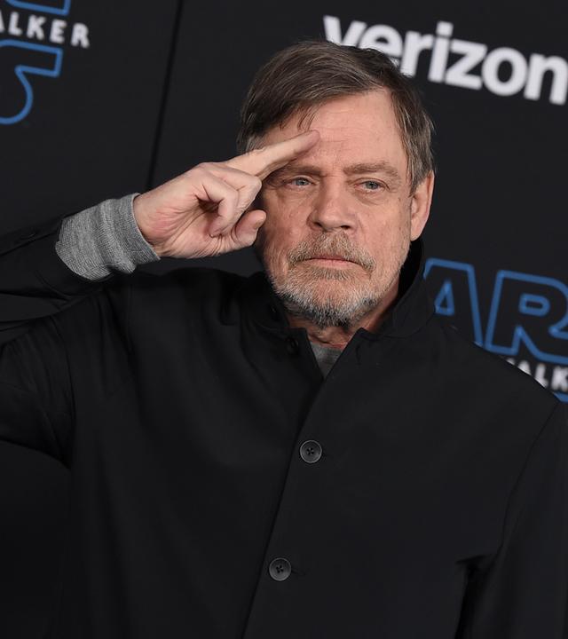 Schauspieler Mark Hamill vor einer Star Wars-Posterwand.
