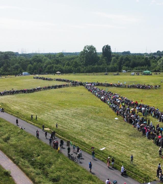 Nordrhein-Westfalen, Hamm: Demonstranten bilden gemeinsam vor der Kulisse eines Kraftwerkes ein Windrad.