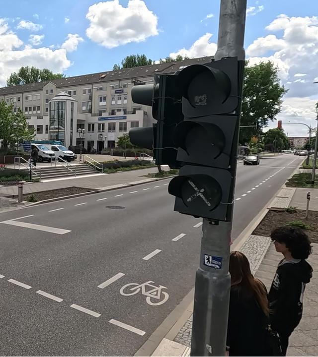 Eine Straße in Hennigsdorf, rechts eine abgeschaltete Ampel, ein Fahrradfahrer überquert die Straße.
