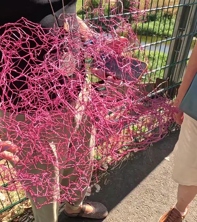 Frau hält Stück eines pinken Kunstwerkes in der Hand