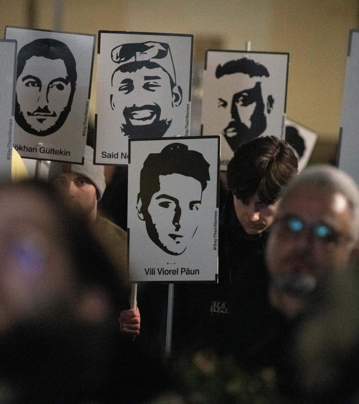 Demonstranten halten Plakate mit stilisierten Bildern der Opfer bei einem Gedenken zum Jahrestag des rassistischen Anschlages von Hanau am damaligen Tatort in Kesselstadt.