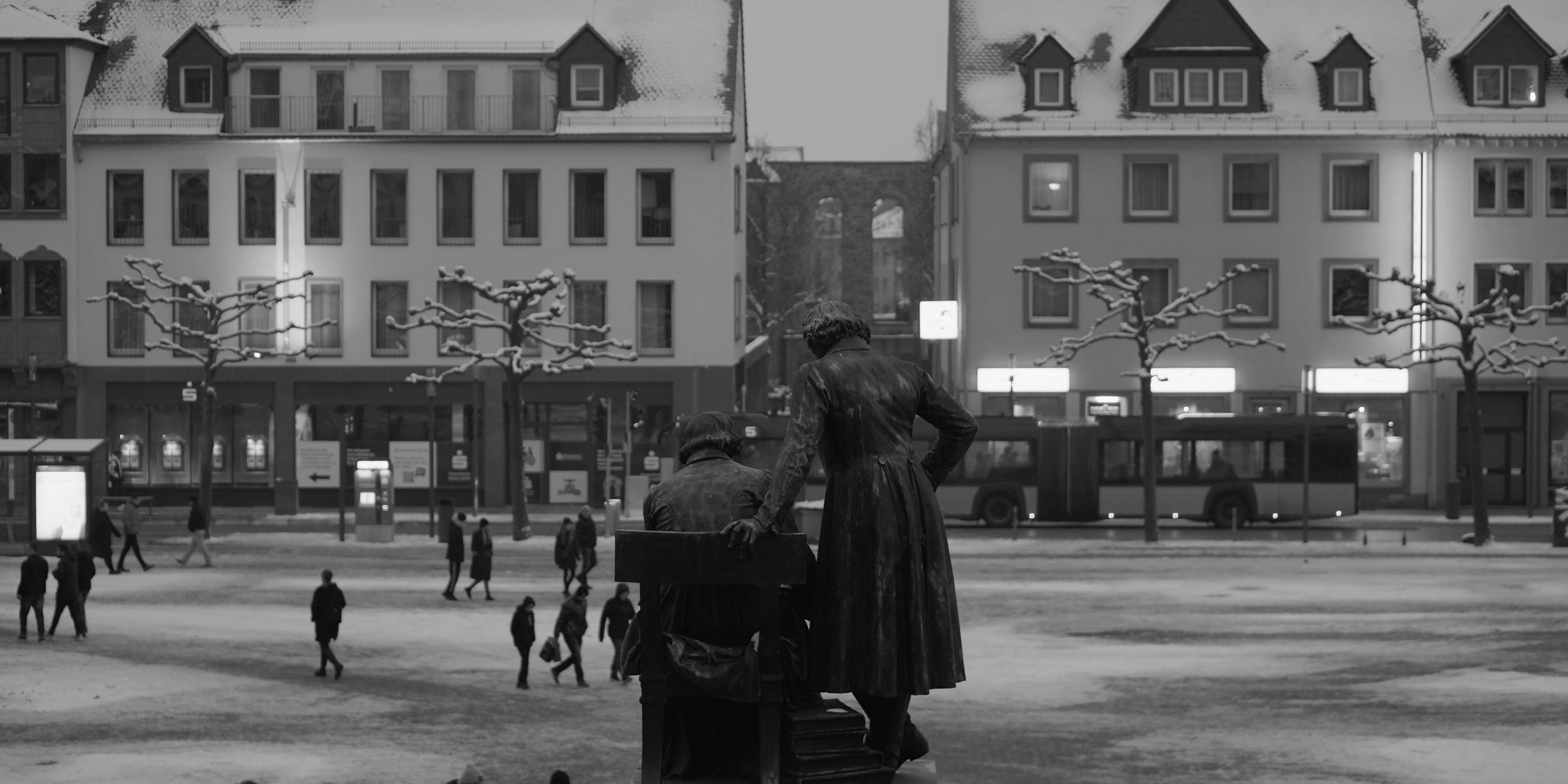 Auf einem Schwarz-Weiß-Bild ist an einem dunklen Winterabend der Marktplatz von Hanau zu sehen.