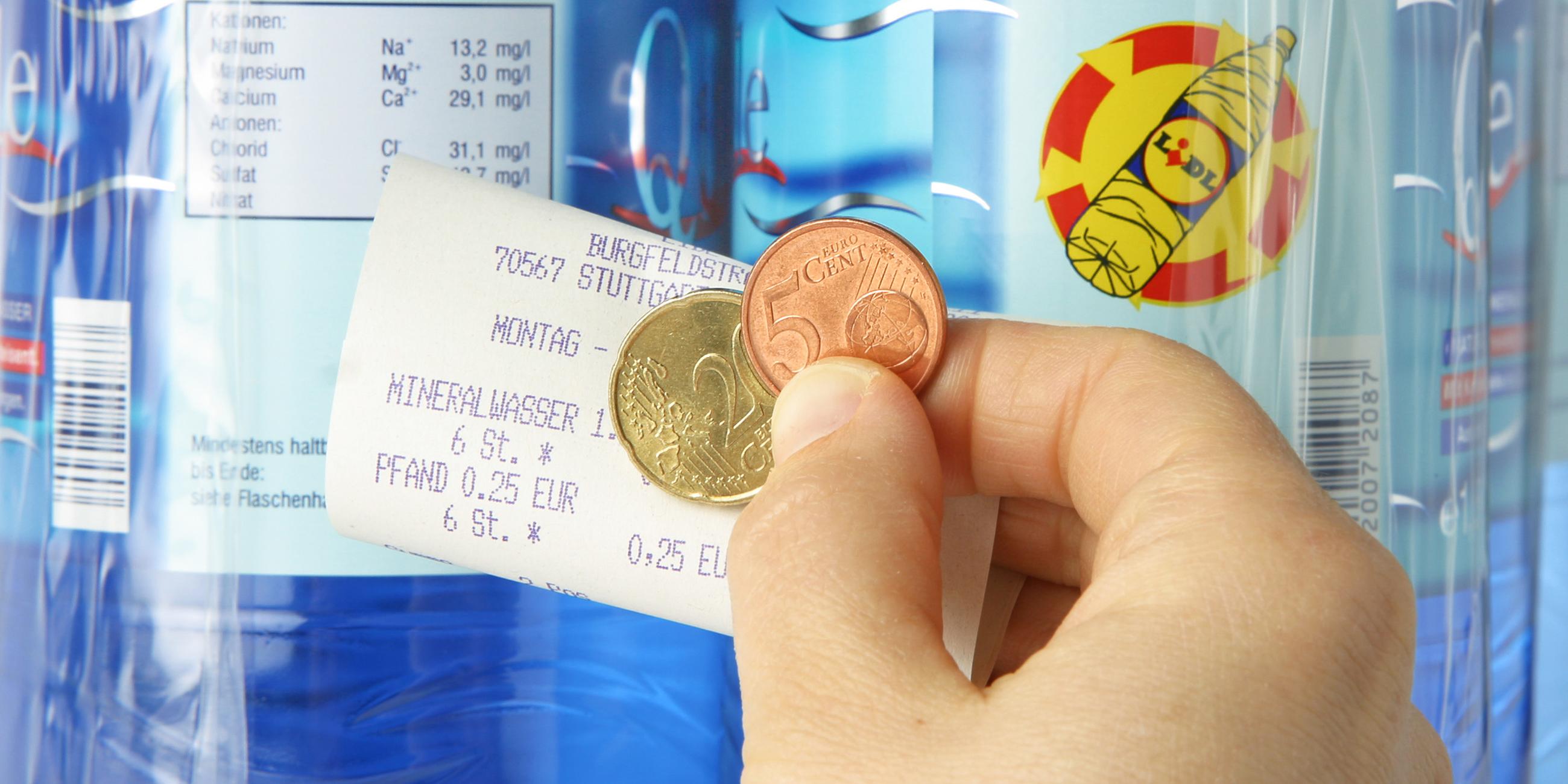 Esslingen, Baden-Württemberg: Hand mit Pfandgeld und Kassenbon vor Mineralwasserflaschen.