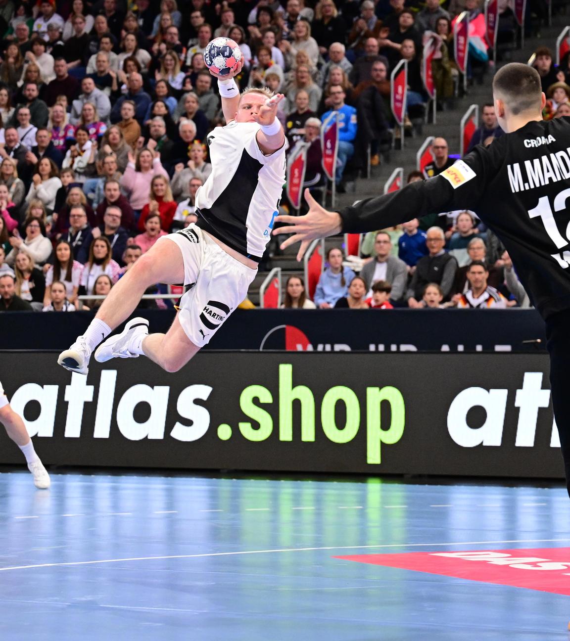 Justus Fischer vollendet einen Konter mit einem Sprungwurf. Kroatiens Torwart Matej Mandic breitet die Arme aus.