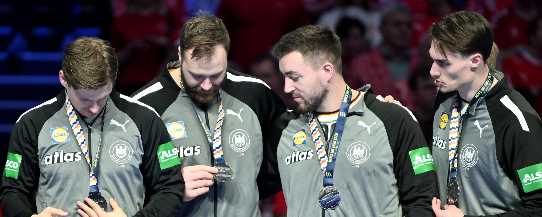 Rune Dahmke, Torhüter Andreas Wolff, Jannik Kohlbacher und Miro Schluroff betrachten die Silbermedaille.