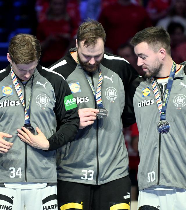 Rune Dahmke, Torhüter Andreas Wolff, Jannik Kohlbacher und Miro Schluroff betrachten die Silbermedaille.