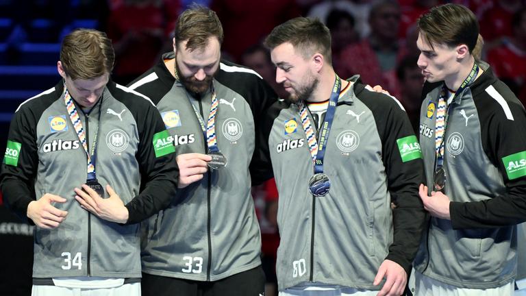 Rune Dahmke, Torhüter Andreas Wolff, Jannik Kohlbacher und Miro Schluroff betrachten die Silbermedaille.