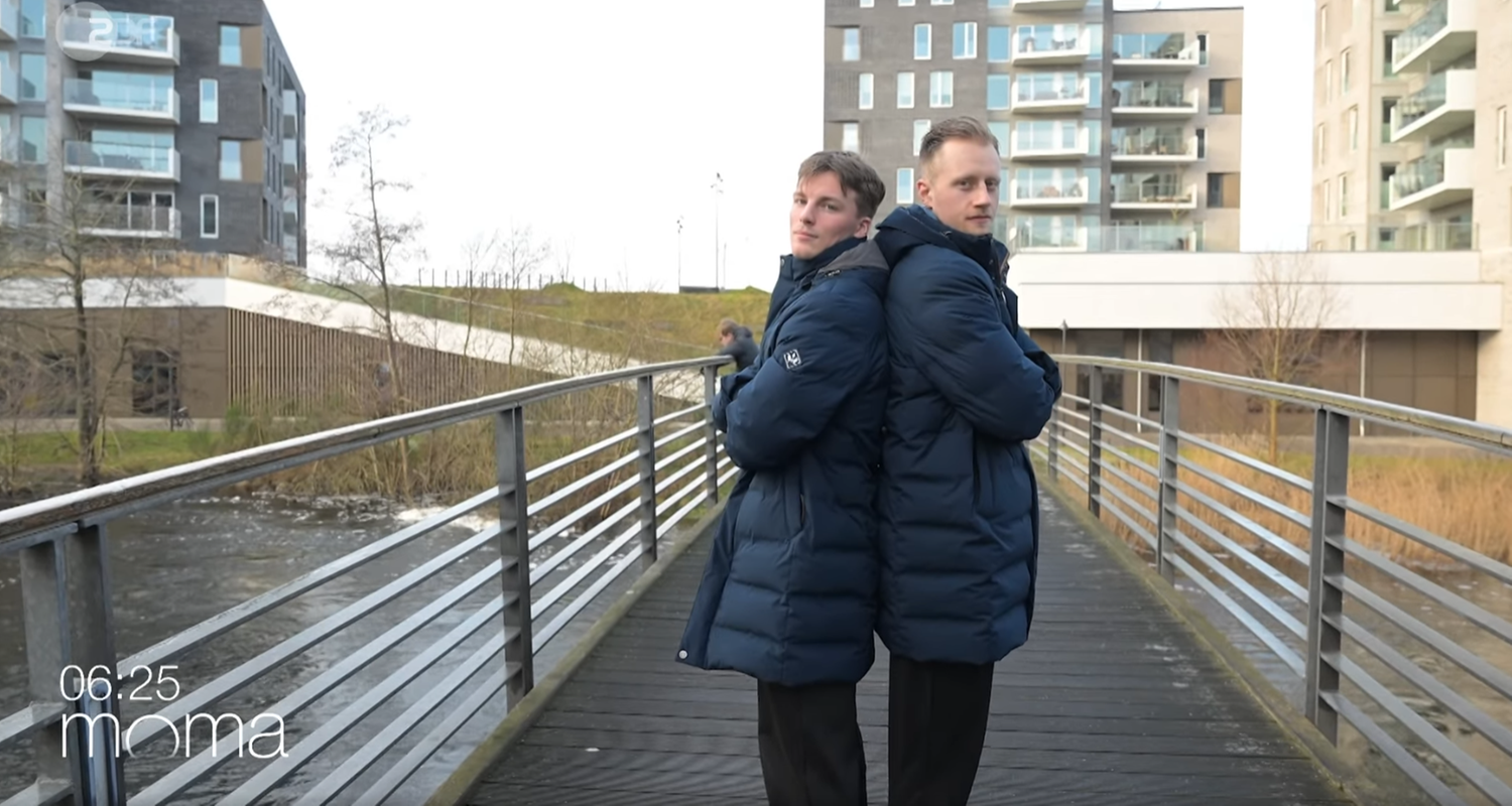 Nils Lichtlein und Luca Witzke stehen dick angezogen und Rücken an Rücken auf einer Fußgängerbrücke.