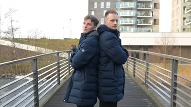 Nils Lichtlein und Luca Witzke stehen dick angezogen und Rücken an Rücken auf einer Fußgängerbrücke.