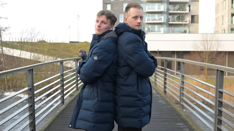 Nils Lichtlein und Luca Witzke stehen dick angezogen und Rücken an Rücken auf einer Fußgängerbrücke.