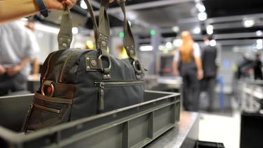 Eine Person nimmt auf dem Flughafen in Duesseldorf ihre Handtasche aus dem Sicherheitscheck.