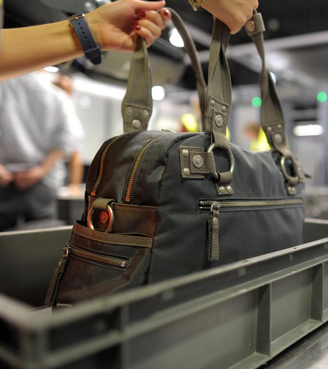 Eine Person nimmt auf dem Flughafen in Duesseldorf ihre Handtasche aus dem Sicherheitscheck.