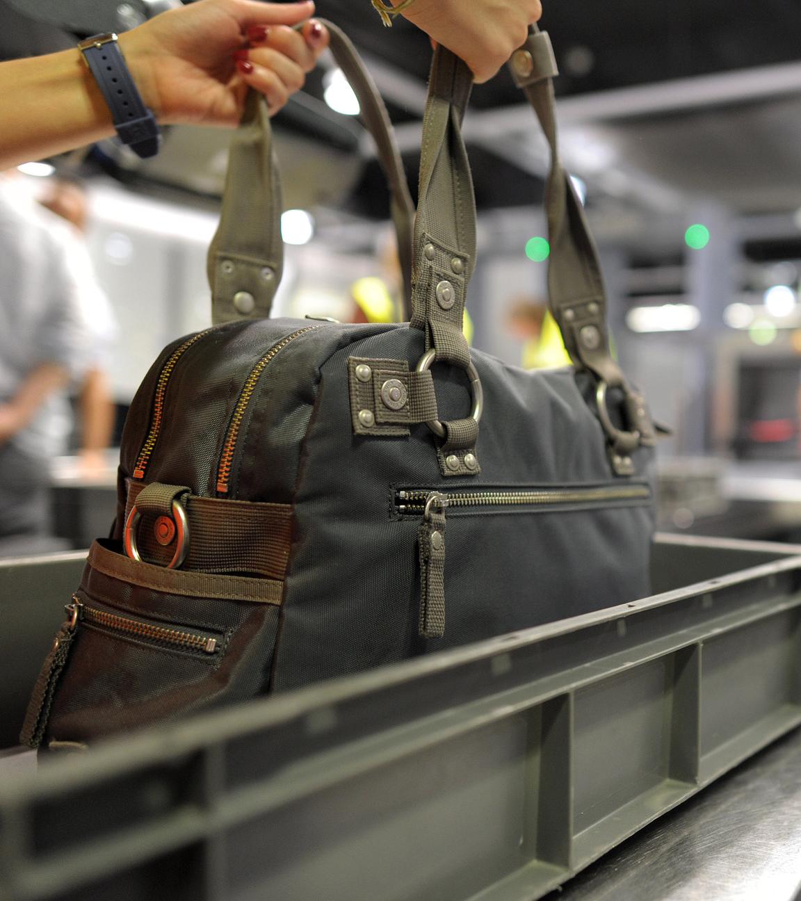 Eine Frau nimmt am 06.07.2012 in dem Flughafen Düsseldorf ihre Handtasche aus dem Fach des Sicherheitschecks.