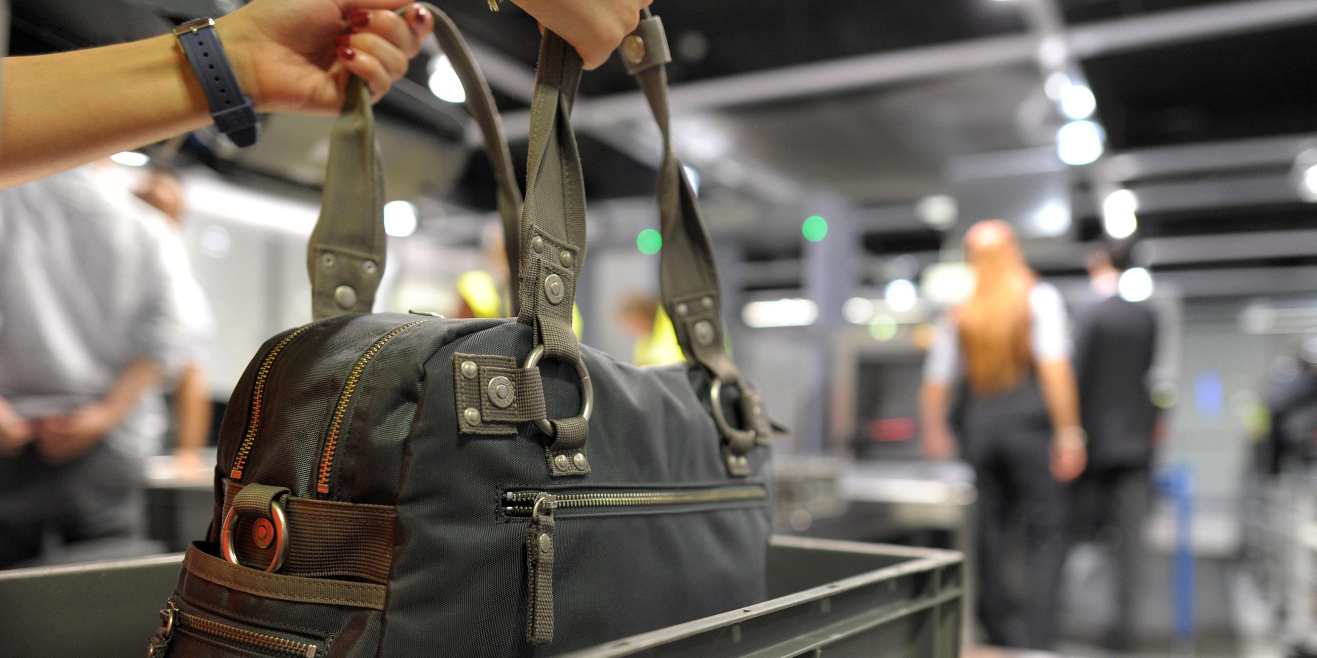 Eine Frau nimmt am 06.07.2012 in dem Flughafen Düsseldorf ihre Handtasche aus dem Fach des Sicherheitschecks.