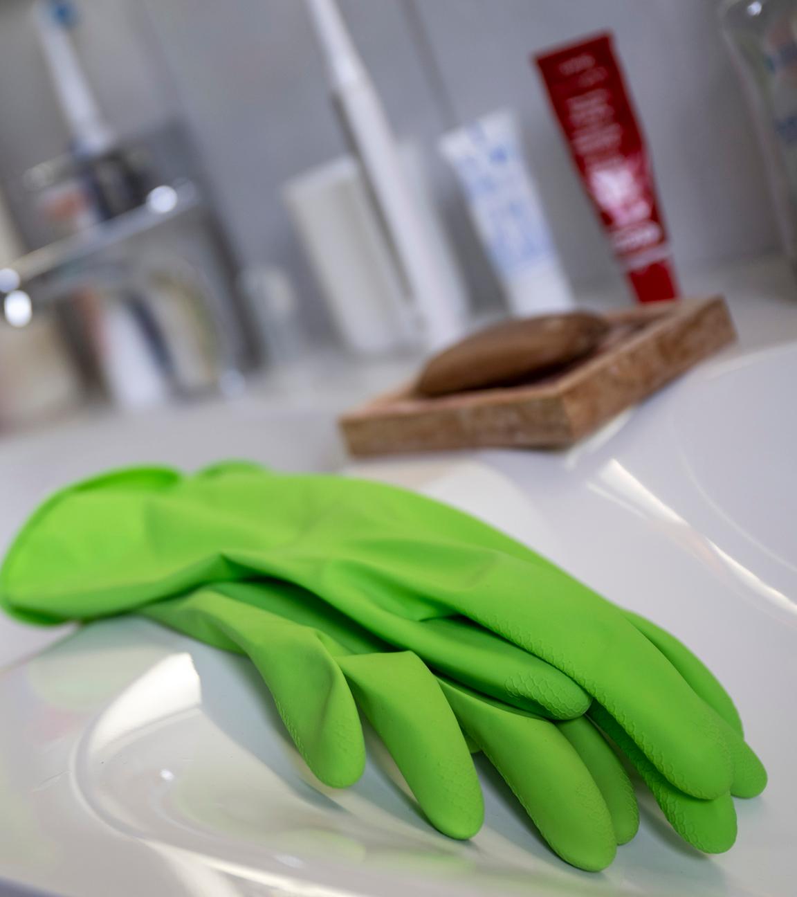 Handschuhe zum Putzen liegen in einem Bad auf dem Waschbecken.