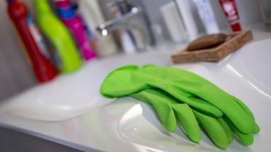 Handschuhe zum Putzen liegen in einem Bad auf dem Waschbecken.