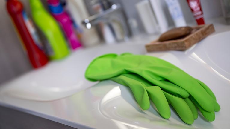 Handschuhe zum Putzen liegen in einem Bad auf dem Waschbecken.