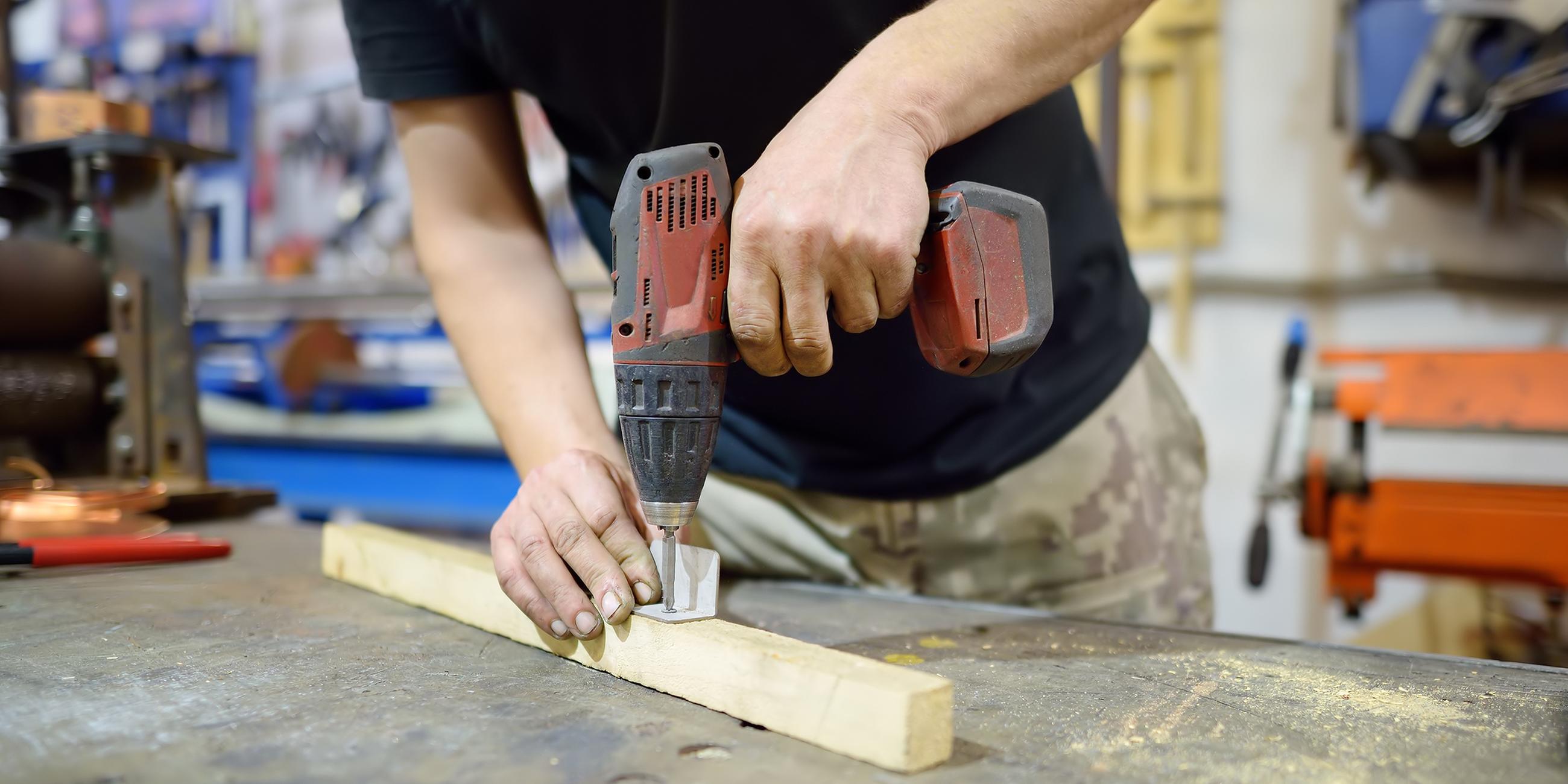 Ein Mann bohrt in ein Stück Holz.