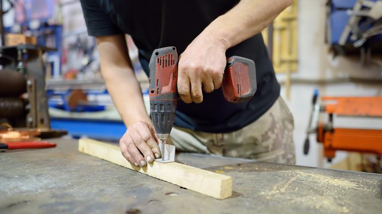 Ein Mann bohrt in ein Stück Holz.