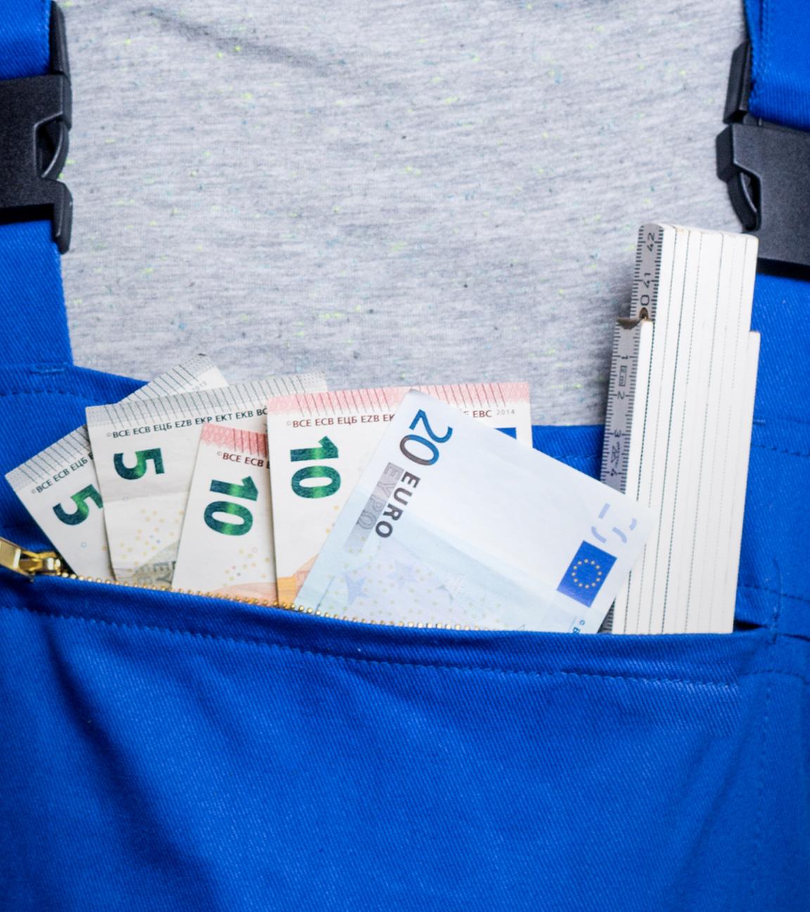 Handwerker mit Blaumann: In der Hosentasche stecken Geldscheine und ein Zollstock