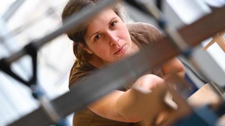 Die 32-Jährige Auszubildende Schreinerin, Anna Freitag, arbeitet an einer Werkbank.