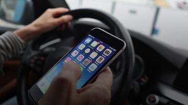 Der Fahrer wird durch das Handy im Auto abgelenkt. (Symbolbild)