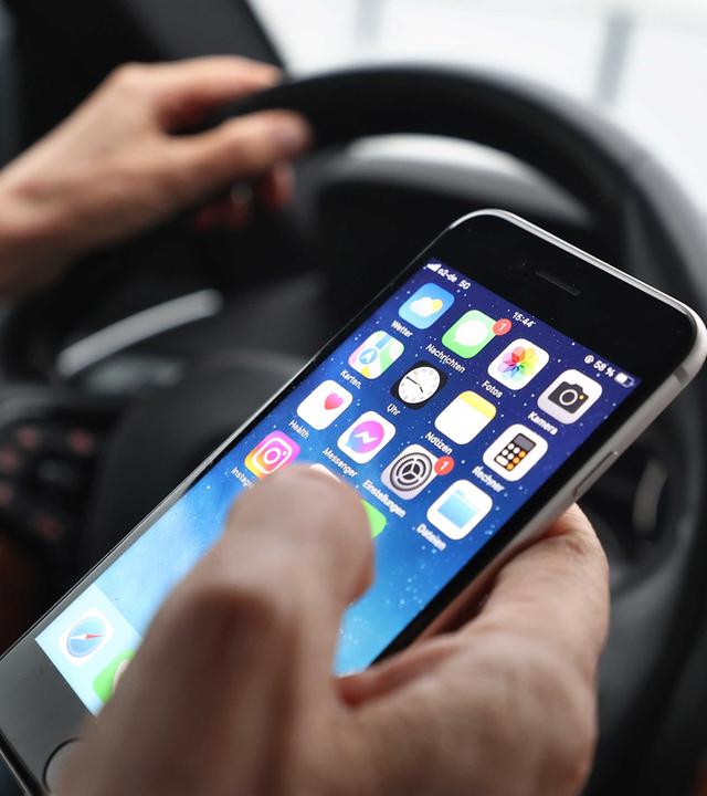 Der Fahrer wird durch das Handy im Auto abgelenkt. (Symbolbild)