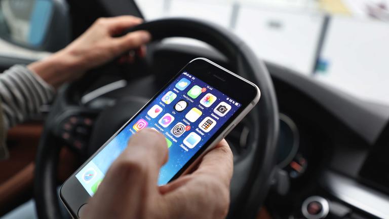 Der Fahrer wird durch das Handy im Auto abgelenkt. (Symbolbild)