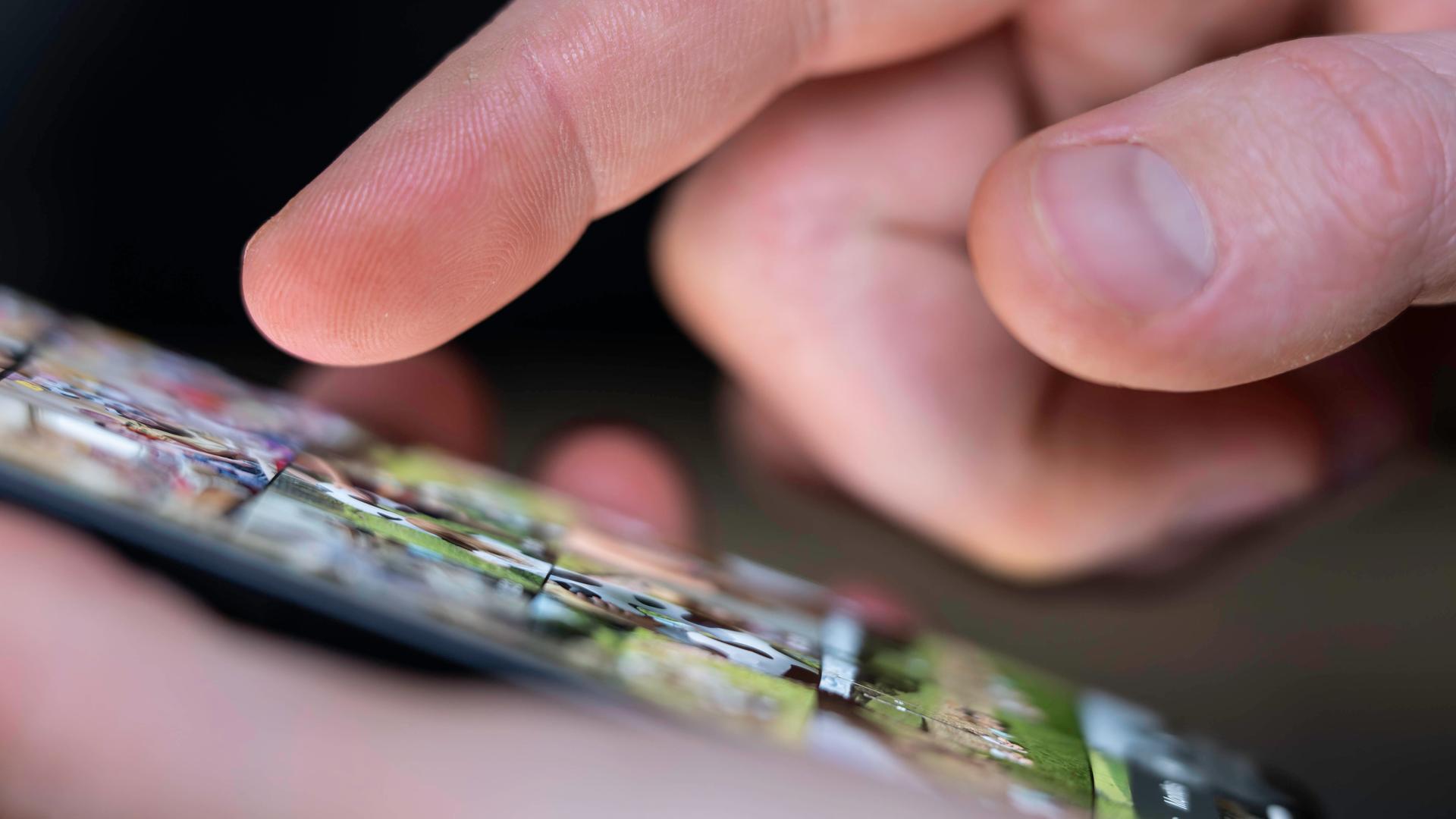 Ein Mann schaut sich die Fotos auf seinem Handy an, indem er seine Foto-App durchscrollt.