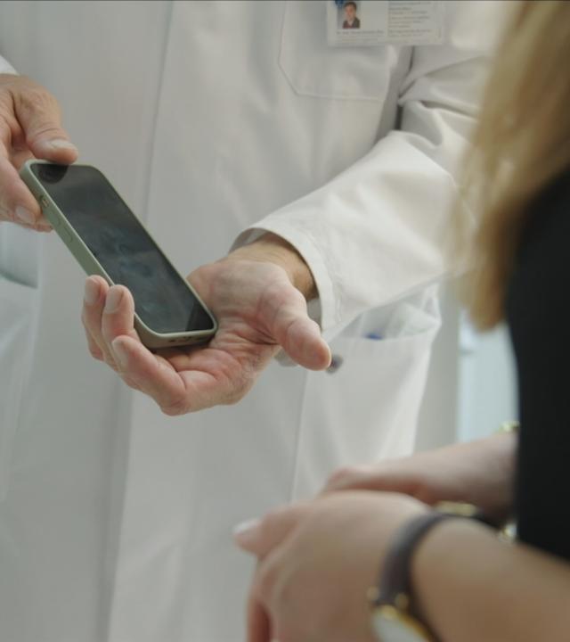 Ein Labormitarbeiter hält ein Handy in der Hand