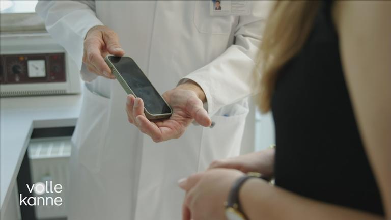 Ein Labormitarbeiter hält ein Handy in der Hand