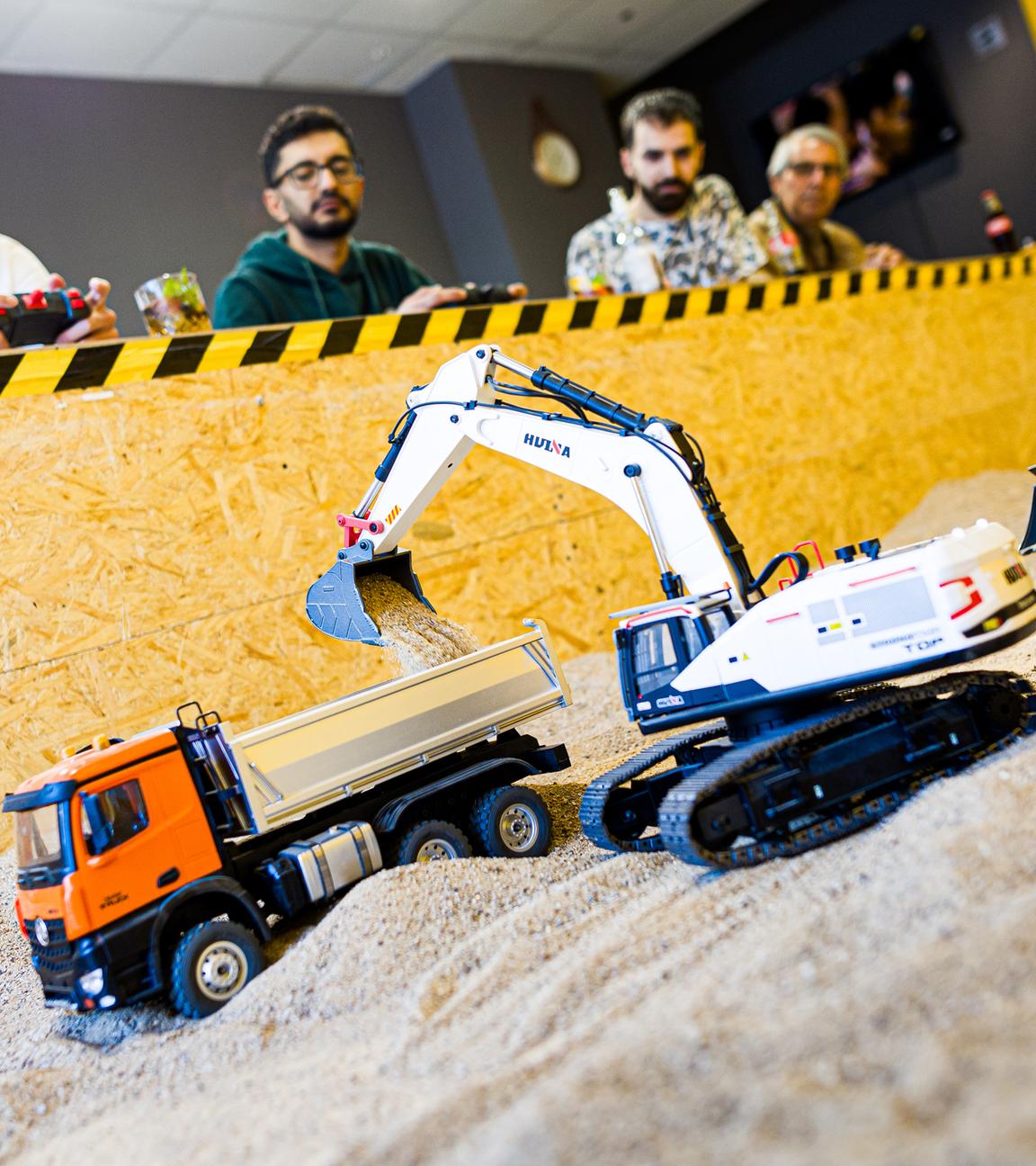 Gründer Siymo Othman steuert mit Freunden Modell-Bagger, -Radlader und -Lastwagen in seinem Bagger-Café.