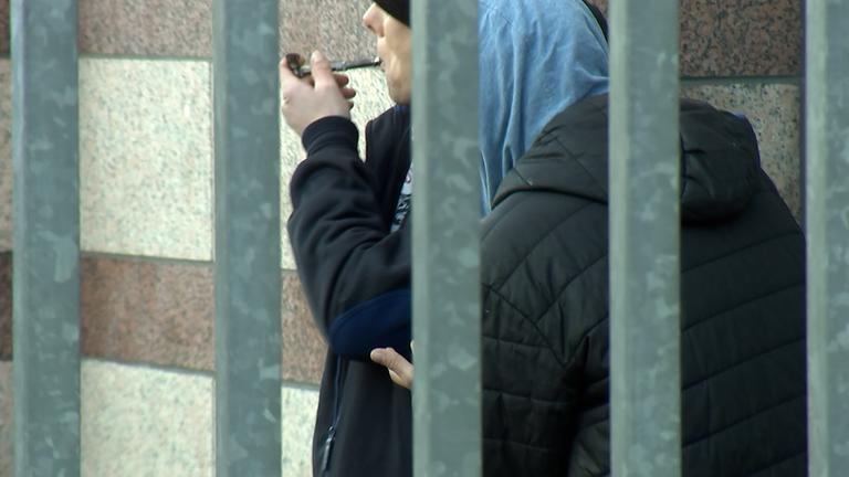 Hinter Eisenstäben sieht man einen Jungen, der Drogen nimmt.