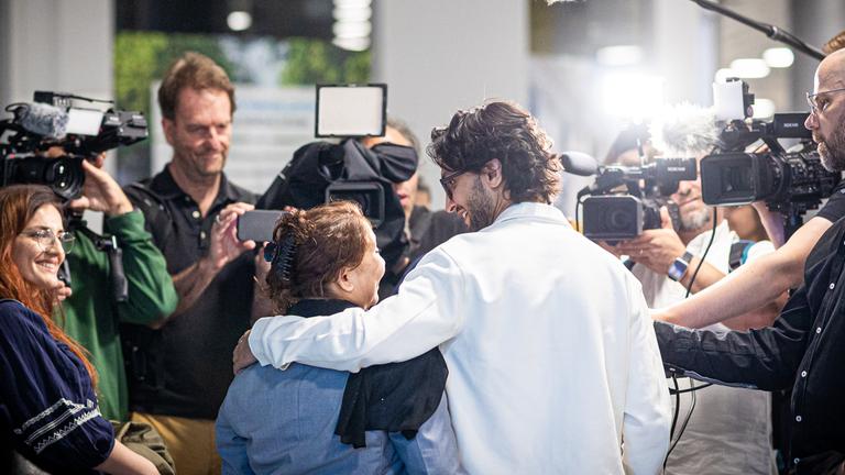 Menschen aus Afghanistan, die zuvor mit einem Flugzeug auf dem Flughafen Hannover-Langenhagen gelandet sind, spechen zu Pressevertretern.