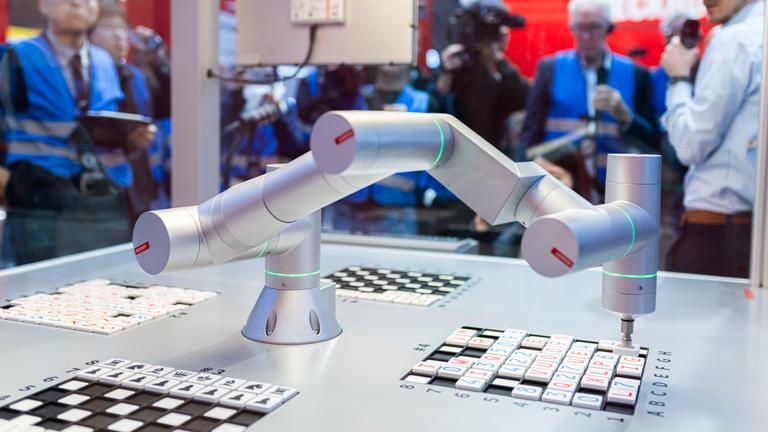 Ein Roboterarm bei einer Demonstration an einem Messestand.