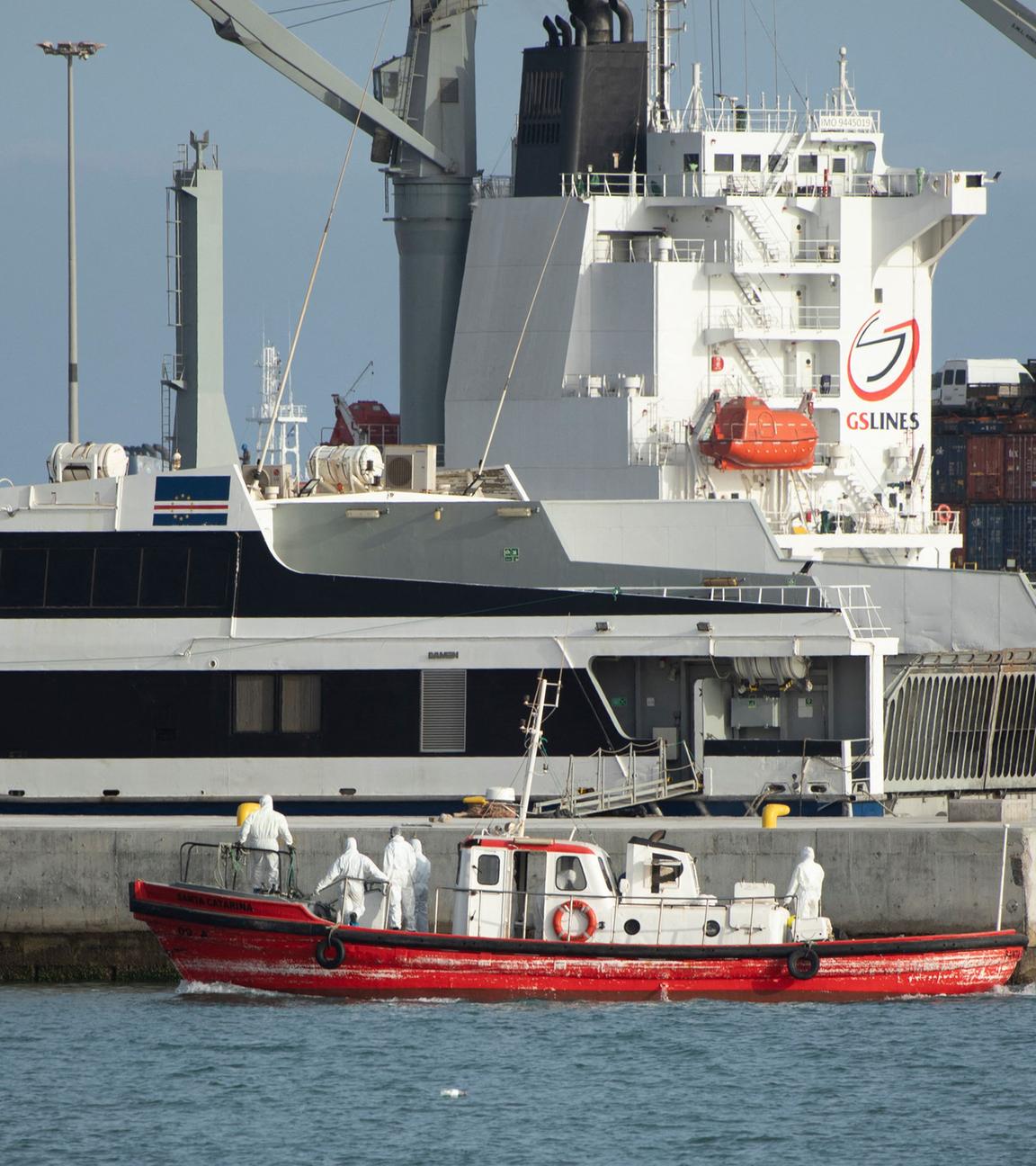 Ein kleines rotes Rettungsboot, darin Menschen in Schutzkleidung, vor dem Kreuzfahrtschiff. 