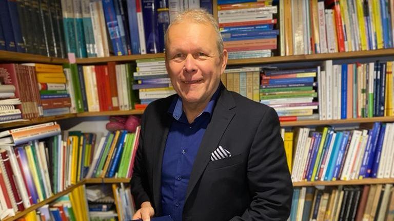 Fanforscher Harald Lange vor einem Bücherregal.