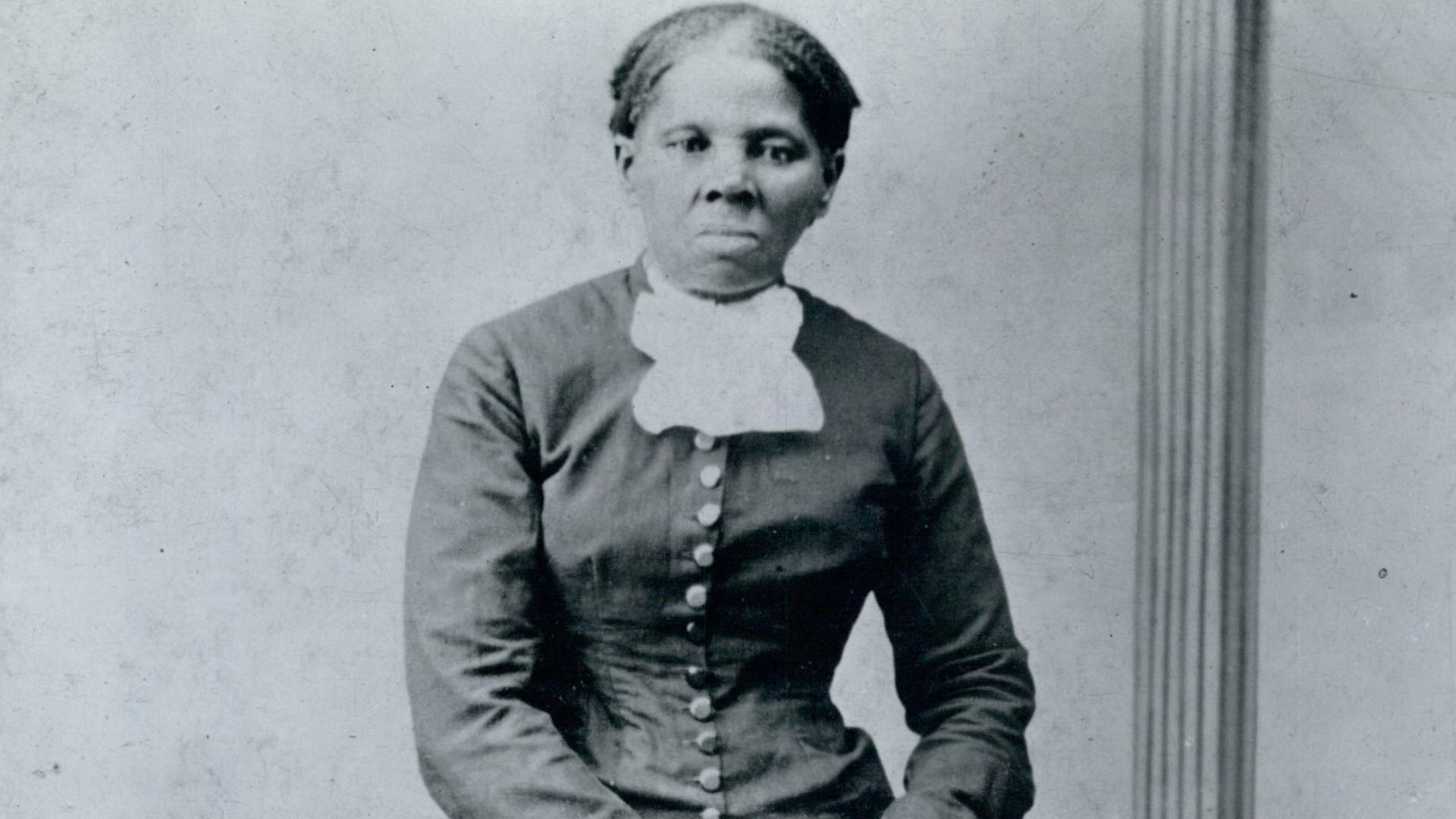 Harriet Tubman posiert für ein Porträt, blickt direkt in die Kamera und stützt ihre Arme auf einen Stuhl