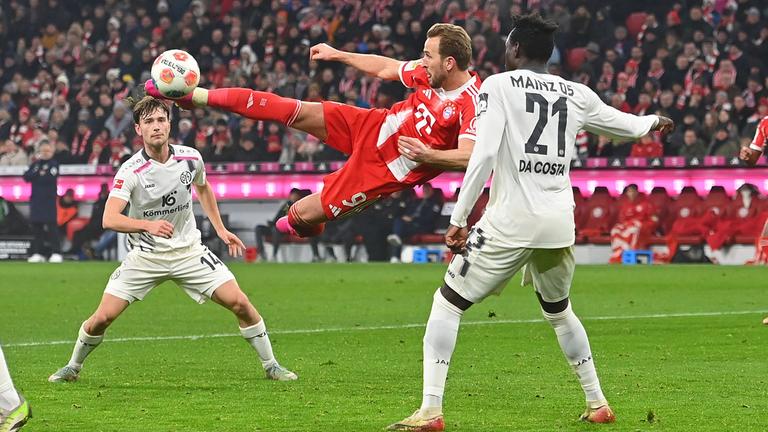 Bayerns Stürmer Harry Kane versucht mit einem Seitfallzieher im Mainzer 16er das Tor zu erzielen.
