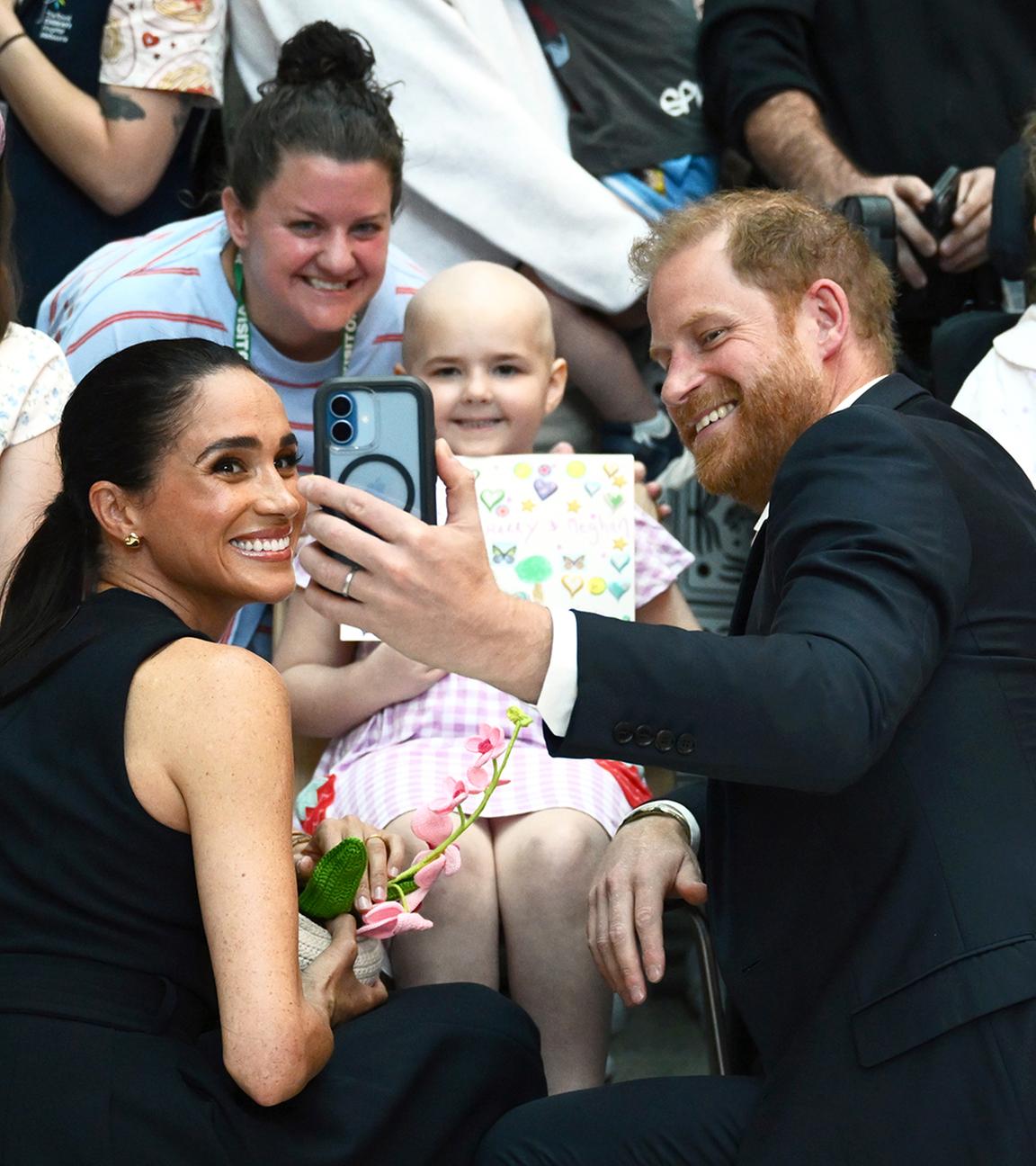 Harry und Meghan machen Fotos mit Fans.