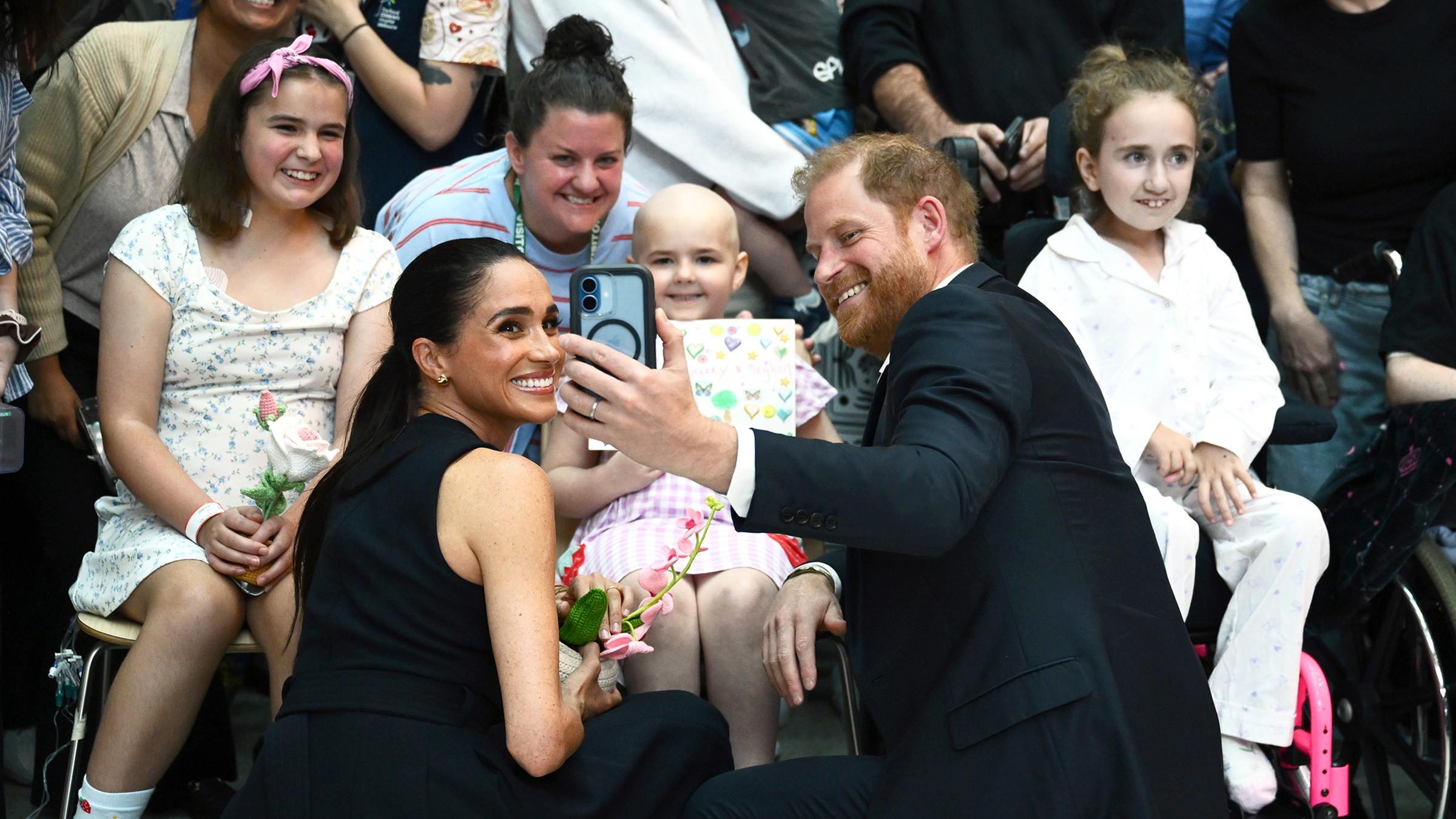 Harry und Meghan machen Fotos mit Fans.